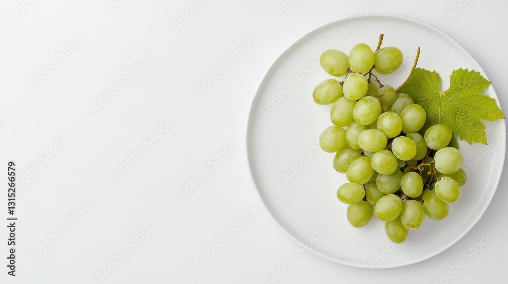 A bunch of fresh green grapes arranged on a white plate, on a white isolated background