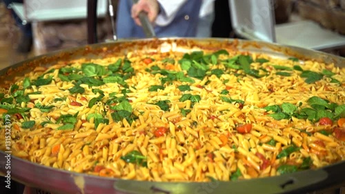 Slow-motion video of a chef expertly tossing a giant pan of sizzling pasta, mixing flavorful ingredients. A culinary spectacle, street food, and gourmet cooking in action.