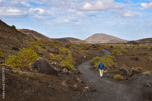 Man walking on  trail in Parque De Los Volcanes National Park. Hiking on the Canary Islands in volcanic landscape. Discover Spain, travel Europe.