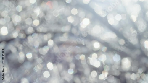 Abstract blurred background with hexagonal bokeh light reflections on frozen tree branches. Soft focus winter scene with shimmering highlights. Nature-inspired texture for design and print.