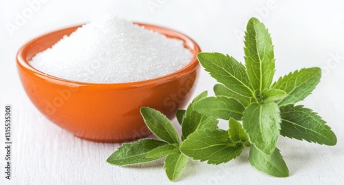 Fresh green stevia leaves beside an orange bowl filled with white granulated sugar on a textured white wooden surface, representing natural sweeteners and healthy living