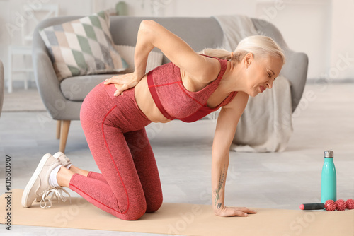 Sporty mature woman suffering from back pain at home