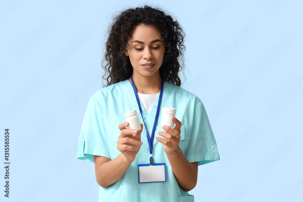 Female African-American medical intern with pill bottles on blue background Female African-American medical intern with pill bottles on blue background