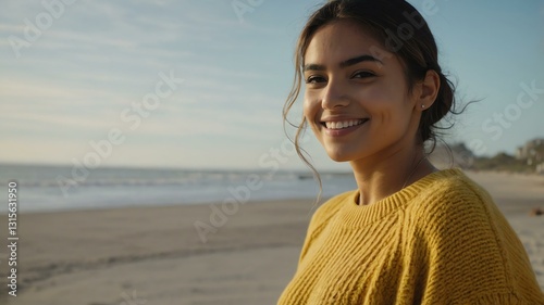 Good-looking young hispanic gal in yellow themed sweater on a beach smiling