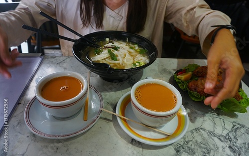Wall Mural A bowl of pho soup, featuring clear broth, noodles, herbs, and tender meat, garnished with fresh ingredients like lime and chili