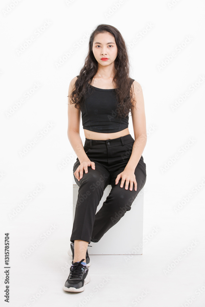 Portrait of asian beautiful woman with curly hair, wearing black tank top black long pants, model girl attractive confident, pose sitting on white box looking at camera on white background in studio. Portrait of asian beautiful woman with curly hair, wearing black tank top black long pants, model girl attractive confident, pose sitting on white box looking at camera on white background in studio.