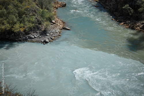 confluence of two rivers of different colors, emerald green and turquoise muddy water, riverside