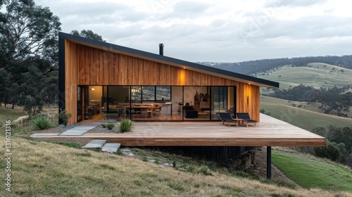 Modern Wood House on Hillside with Deck and Scenic View of Rolling Hills Under Cloudy Sky Architecture