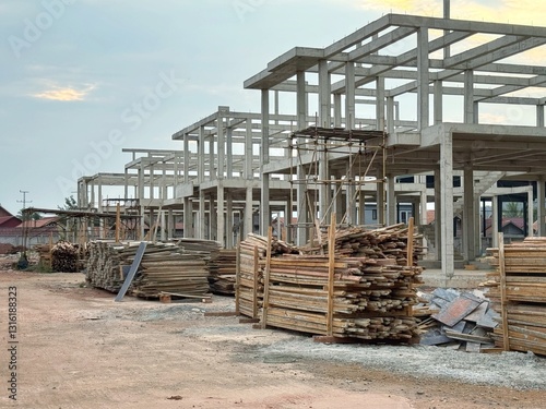 Reinforced steel and concrete building under construction, lumber pilling up.