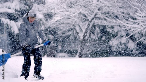 Active Senior Clearing Snow with Blue Shovel During Beautiful Snowstorm. Slow Motion Winter Scene of Elderly Woman Maintaining Yard in Heavy Snow