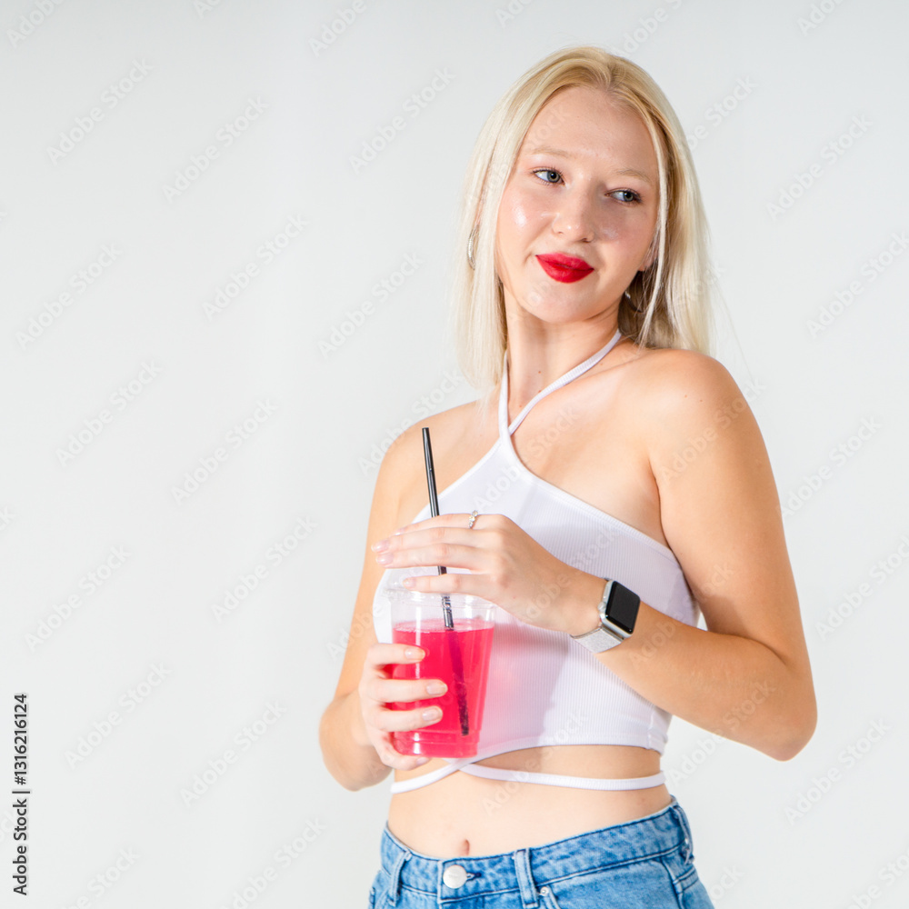 Attractive young blonde holding a pink cocktail. She is wearing a white top and blue jeans on a white background. Copy space Attractive young blonde holding a pink cocktail. She is wearing a white top and blue jeans on a white background. Copy space