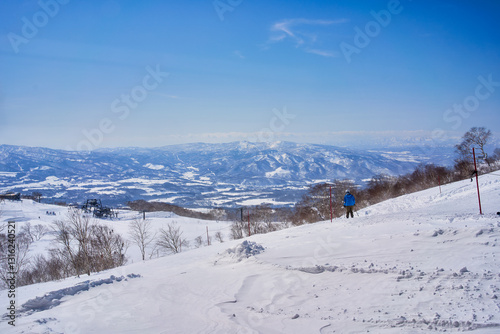 Traveller try to sky on snowy volcano with cap cloud viewed from a ski resort at niseko sapporo japan.