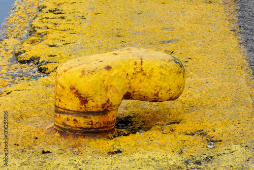 Yellow mooring bollard securing ships at the dock