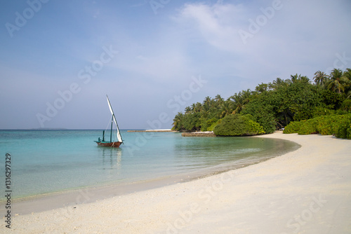 Sail boat on turquoise water and white sandy beach, tropical setting