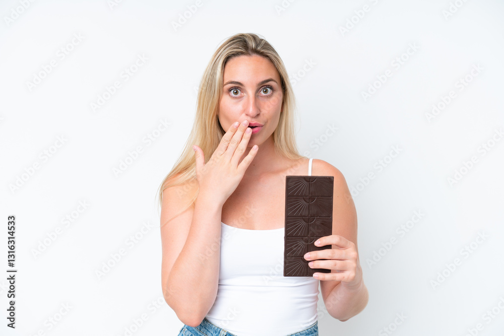 Young caucasian woman isolated on white background taking a chocolate tablet and surprised