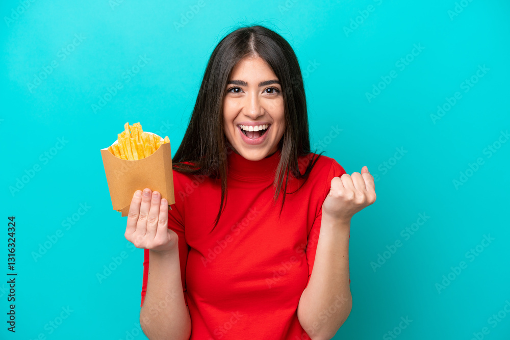 Young caucasian woman catching french fries isolated on blue background celebrating a victory in winner position Young caucasian woman catching french fries isolated on blue background celebrating a victory in winner position