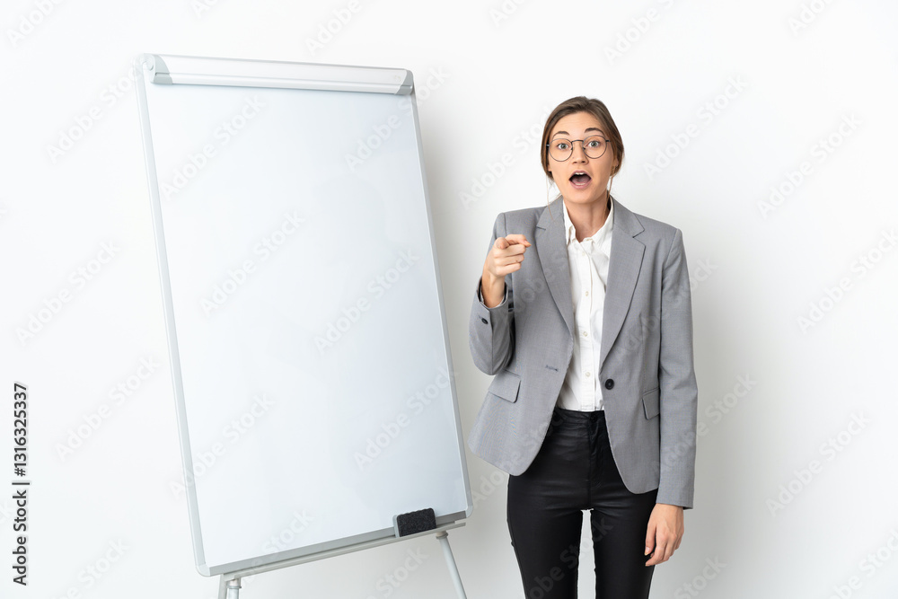 Young Ireland woman isolated on white background giving a presentation on white board and surprised while pointing front Young Ireland woman isolated on white background giving a presentation on white board and surprised while pointing front