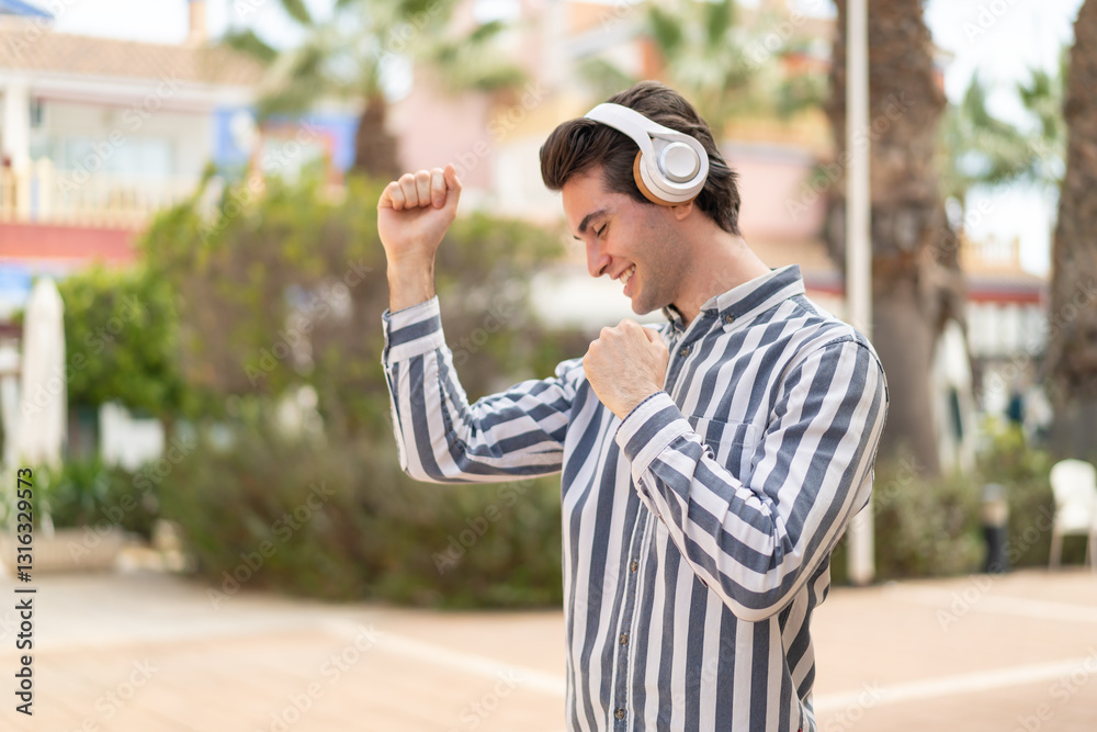 Obraz premium Young handsome man listening music and dancing