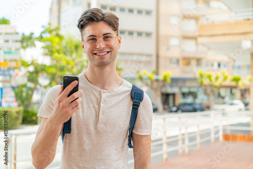 Wallpaper Mural Young handsome man using mobile phone at outdoors smiling a lot Torontodigital.ca