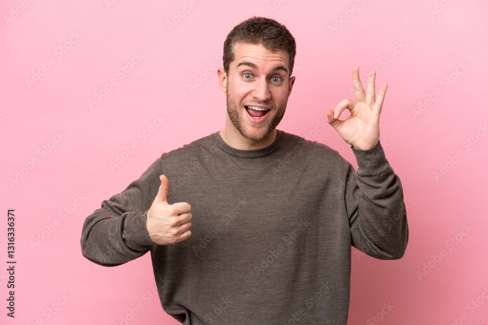 Fototapeta premium Young caucasian man isolated on pink background showing ok sign and thumb up gesture