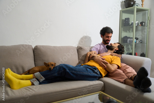 Gay couple relaxing on sofa with their dog embracing domesticity