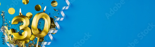 Celebrating 30 years. Golden burning candle in form of number thirty on celebration festive blue background lying in sparkles. Holiday banner with copy space. photo