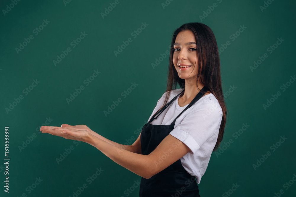 Copy space, showing invisible object. Young beautiful barista is against background Copy space, showing invisible object. Young beautiful barista is against background