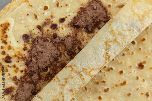 A close-up of a crêpe sprinkled with cocoa powder.