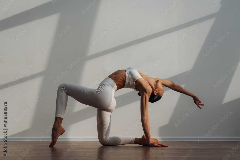Obraz premium Sportive yoga exercise for flexibility. Beautiful young woman with slim body type is indoors