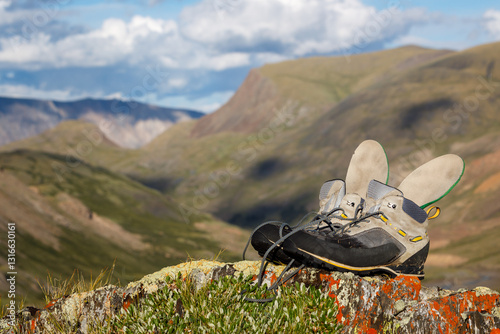 Hiking boots with insoles drying in the sun in the mountains. Boots in focus, background blurred. Copy space.