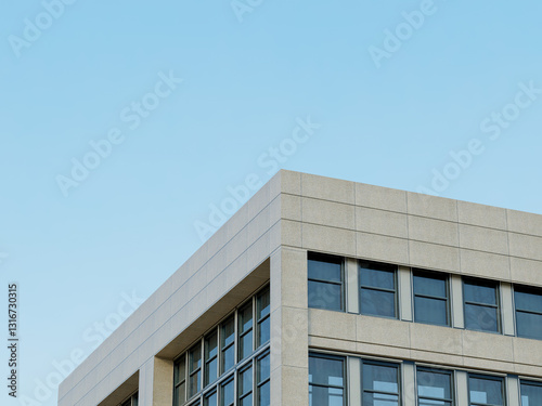 Glass facade of a modern building with geometric design and clear sky.
