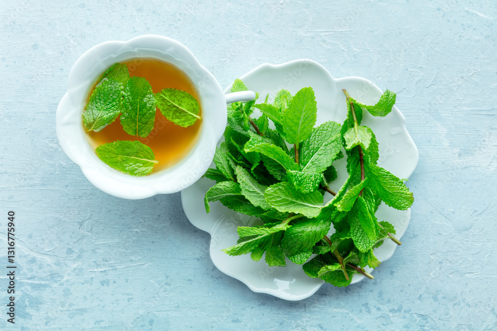 Mint tea. A cup of peppermint tea with fresh mint leaves, shot from above on a blue background Mint tea. A cup of peppermint tea with fresh mint leaves, shot from above on a blue background