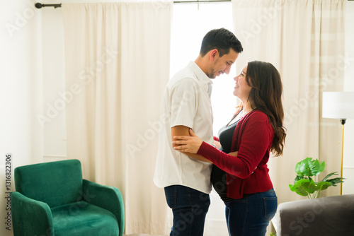 Принти на полотні Pregnant latina woman receiving loving embrace from partner while gently touchin