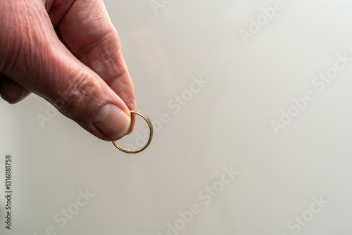 Photos Hand is holding a wedding ring, showing signs of wearing it for a long time, with the fingertips, as if he wants to drop it, let it go
