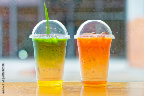 Thai Milk Tea and Matcha Drink in Plastic Cups. A vibrant pair of iced beverages featuring Thai tea and a matcha-based drink, served in clear plastic cups with dome lids.