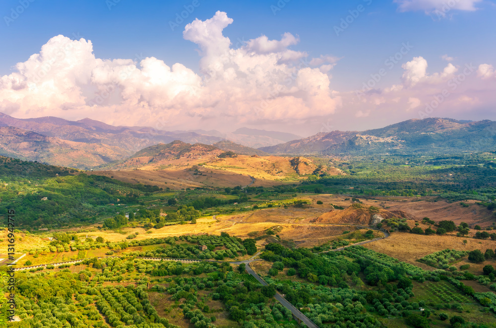 Fototapeta premium scenic rustic landscape with green hills and farms in a mountain valley during colorful cloudy sunset