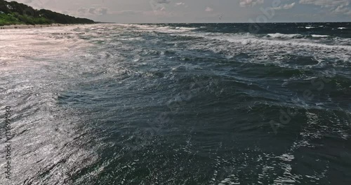 Kitesurfer riding on big waves at Baltic Sea.