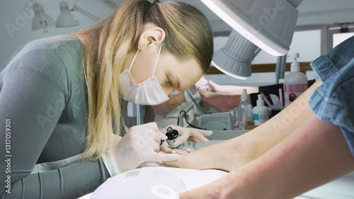 Group of professional podiatrists working in a modern nail beauty studio or spa. Satisfied clients relaxing and enjoying in a great foot and toenails treatment. 