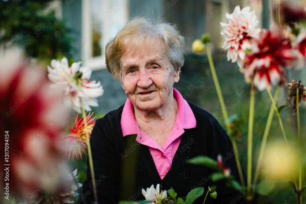 A portrait of an elderly woman in a garden surrounded by blooming flowers, radiating warmth and serenity in a natural setting.