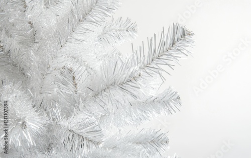 Close-up of white Christmas tree with silver ornaments and tinsel on white background, soft shadows and sharp focus