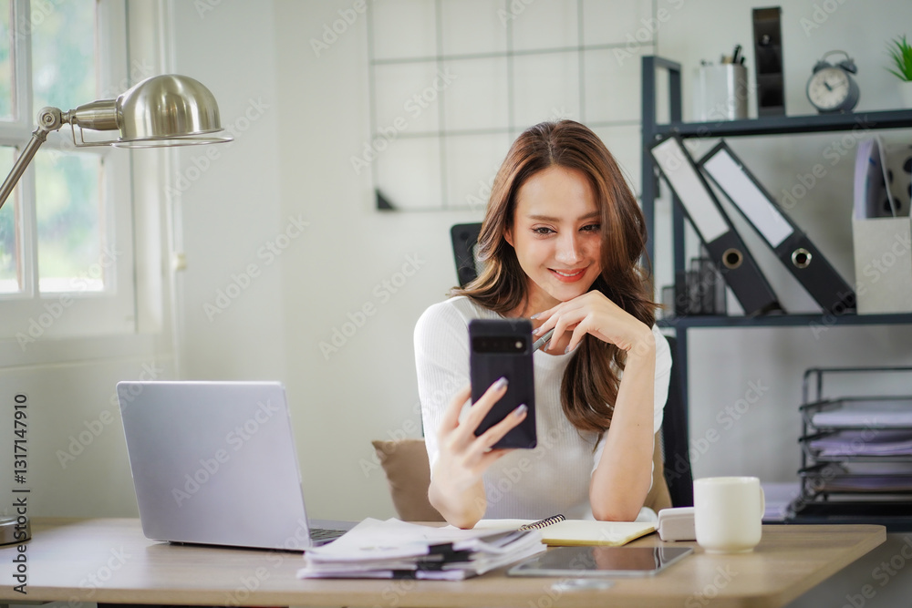 A woman is sitting at a desk with a laptop and a cell phone A woman is sitting at a desk with a laptop and a cell phone