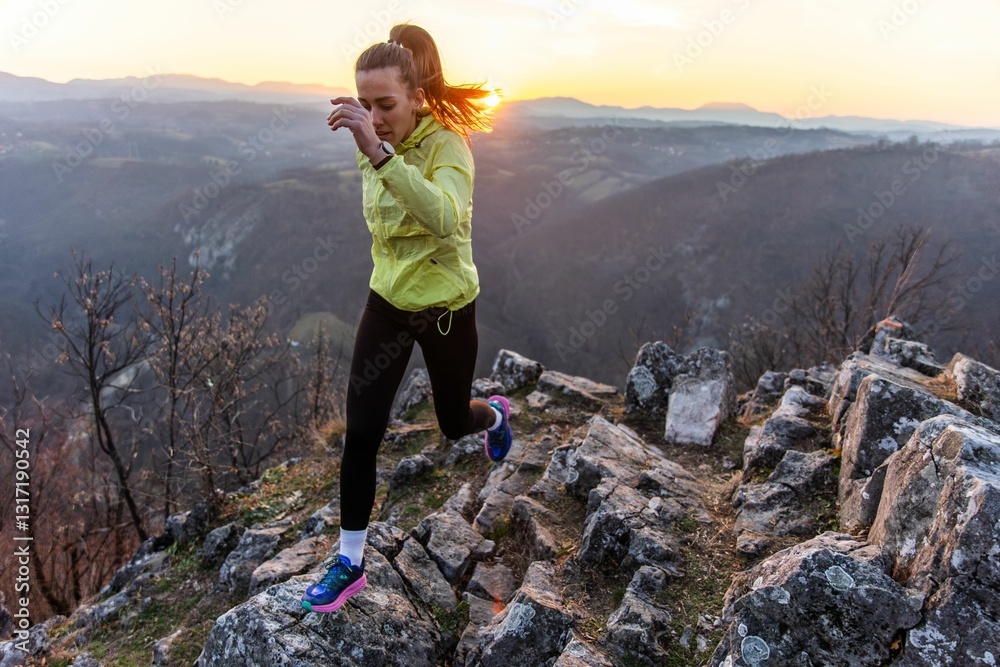 Naklejka premium Woman jogging on mountain trail at sunset.