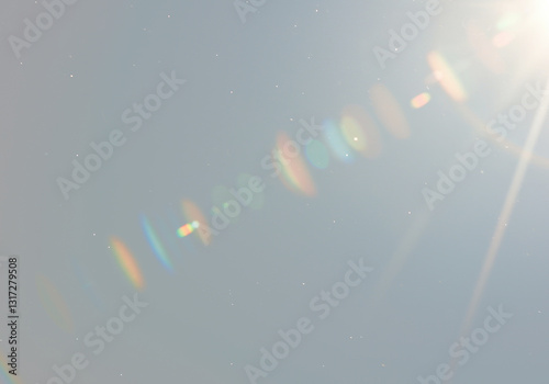 Bright lens flare effect with diagonal streak of white light, spectral rainbow bokeh, grainy dust particles on transparent background