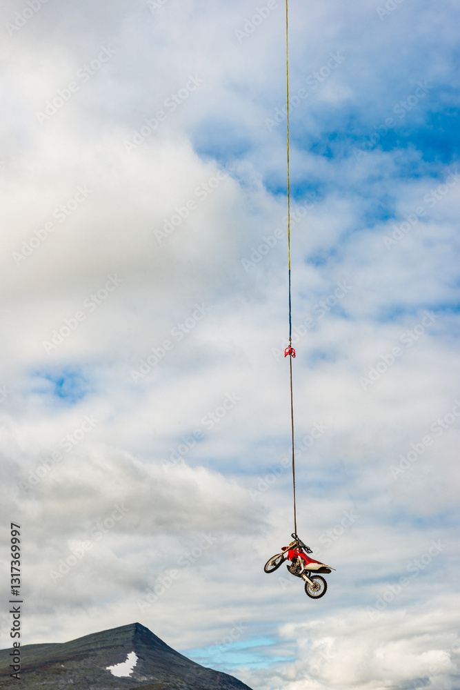 Motorcycle suspended in the air over rugged Swedish landscape with dramatic clouds Motorcycle suspended in the air over rugged Swedish landscape with dramatic clouds