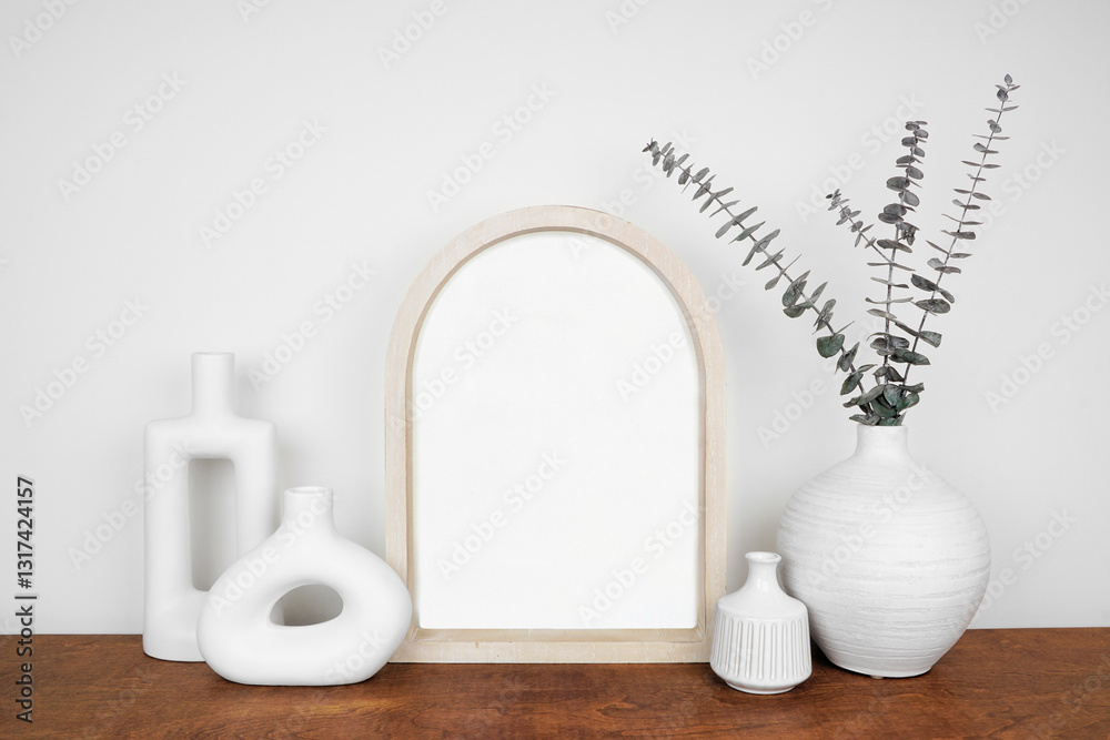 Mock up wooden arched portrait frame with modern vase decor. Wood shelf against a white wall. Copy space.