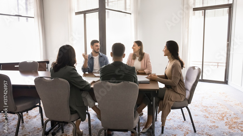 Group of five professionals sitting around conference table solve work-related matters, exchanging opinions, sharing point or feedback, planning collaboration gathered in meeting room. Seminar event