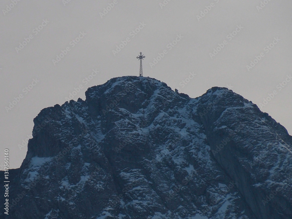Fototapeta premium Snowy Cross on Alpine Summit under Clear Blue Sky