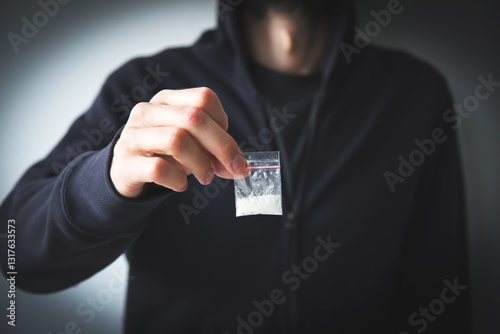 man in sweatshirt and hoodie faceless holds small bag with white substance - drug, concept of drug addiction, dependence and distribution