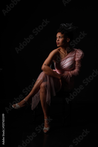 Wallpaper Mural Low key portrait of young curly woman in pink dress sitting in a chair Torontodigital.ca