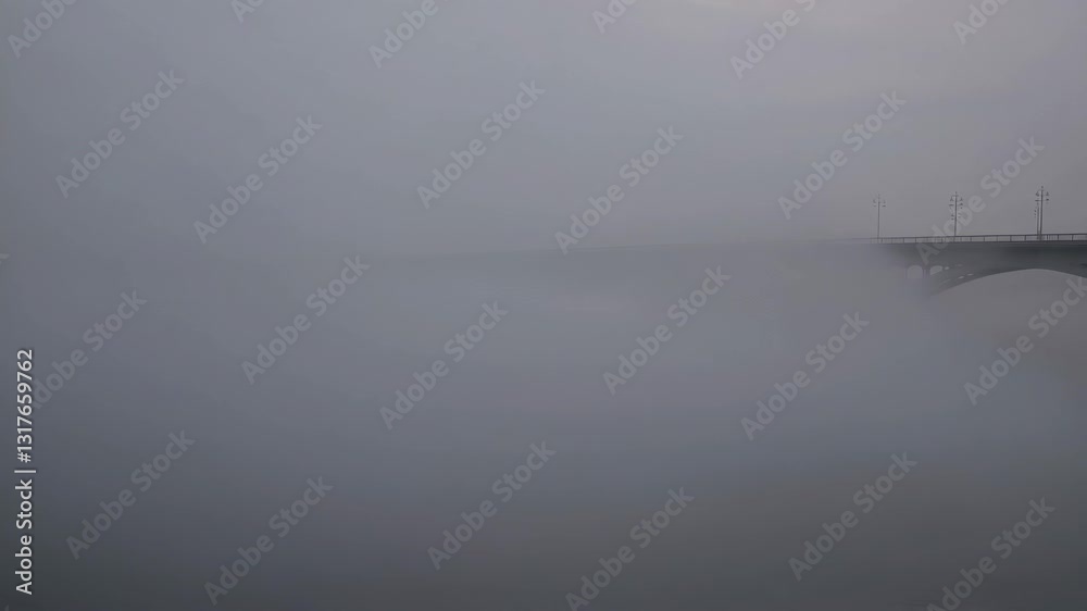 Fog envelops bridge at dawn creating a mystical atmosphere in early morning light Fog envelops bridge at dawn creating a mystical atmosphere in early morning light